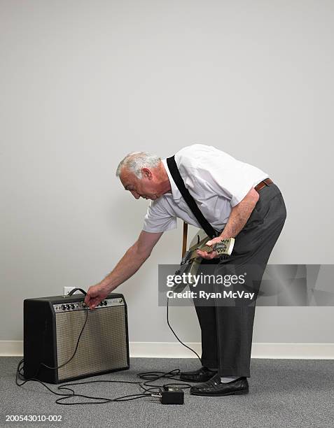 senior businessman with electric guitar adjusting amplifier - old amplifier stock pictures, royalty-free photos & images