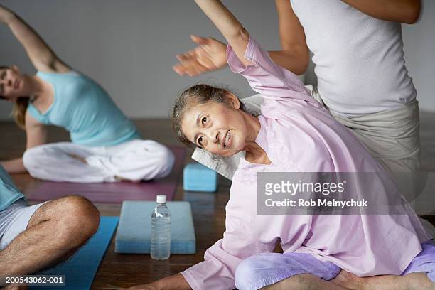 Group of people stretching in yoga class, arms raised