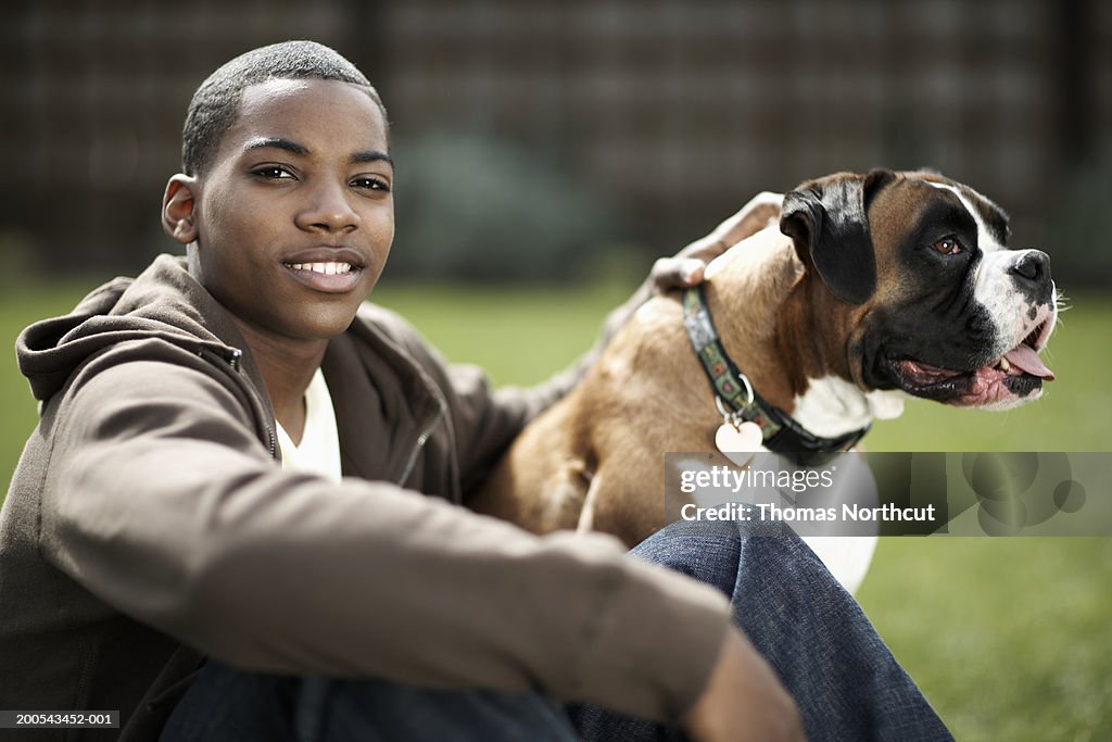 Teenage boy (14-16) and dog outdoors, boy smiling