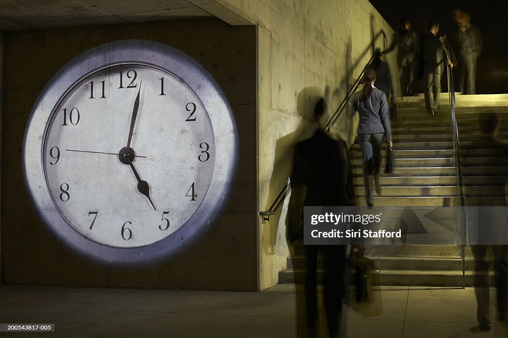 Business people on staircase, clock projected on wall