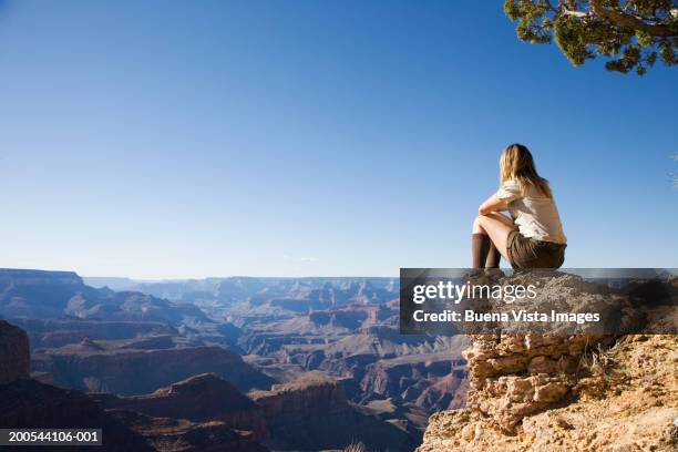 usa, arizona, grand canyon, woman sitting on cliff looking at canyon - grand canyon stock-fotos und bilder