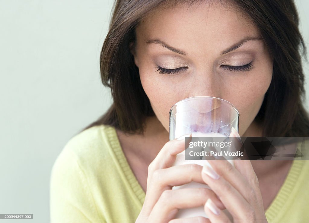 Young woman drinking milk, smiling, close-up