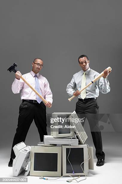 two businessmen holding sledgehammer and baseball bat, near pile of old technology - sledgehammer stockfoto's en -beelden