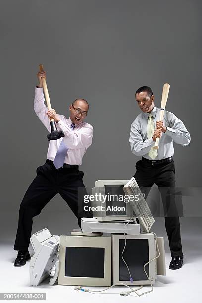 two businessmen holding sledgehammer and baseball bat, near pile of old technology - sledgehammer stockfoto's en -beelden