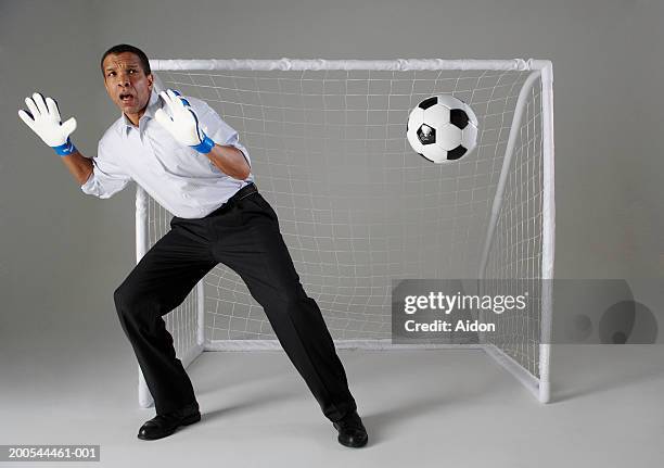 businessman playing goalkeeper, missing ball, studio shot - bad goalkeeper stock pictures, royalty-free photos & images