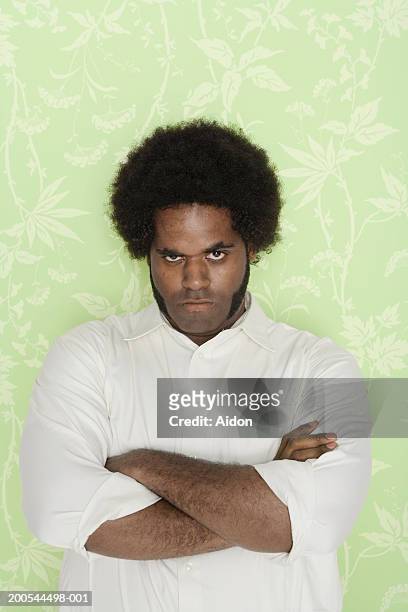 man with arms crossed, against wallpaper background, portrait - basetta foto e immagini stock