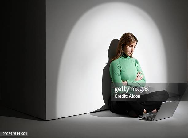 woman with arms crossed, using laptop - spotlight person stock pictures, royalty-free photos & images