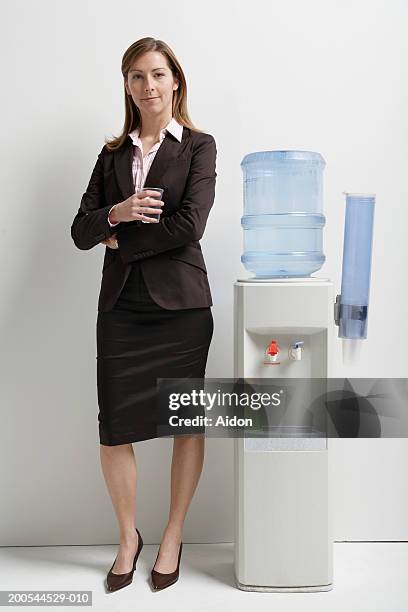 businesswoman standing by water cooler, portrait - water cooler stock pictures, royalty-free photos & images