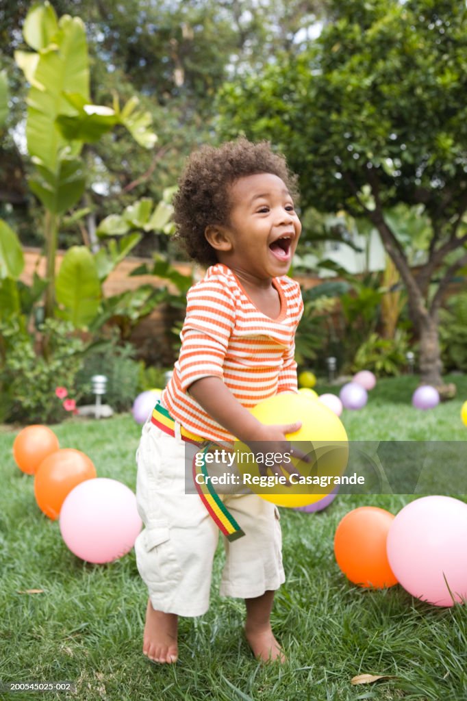 Toddler boy (21-24 months) playing with balloons in yard