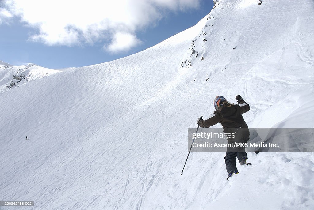 Girl (10-11) skiing on snowy hill slope, rear view