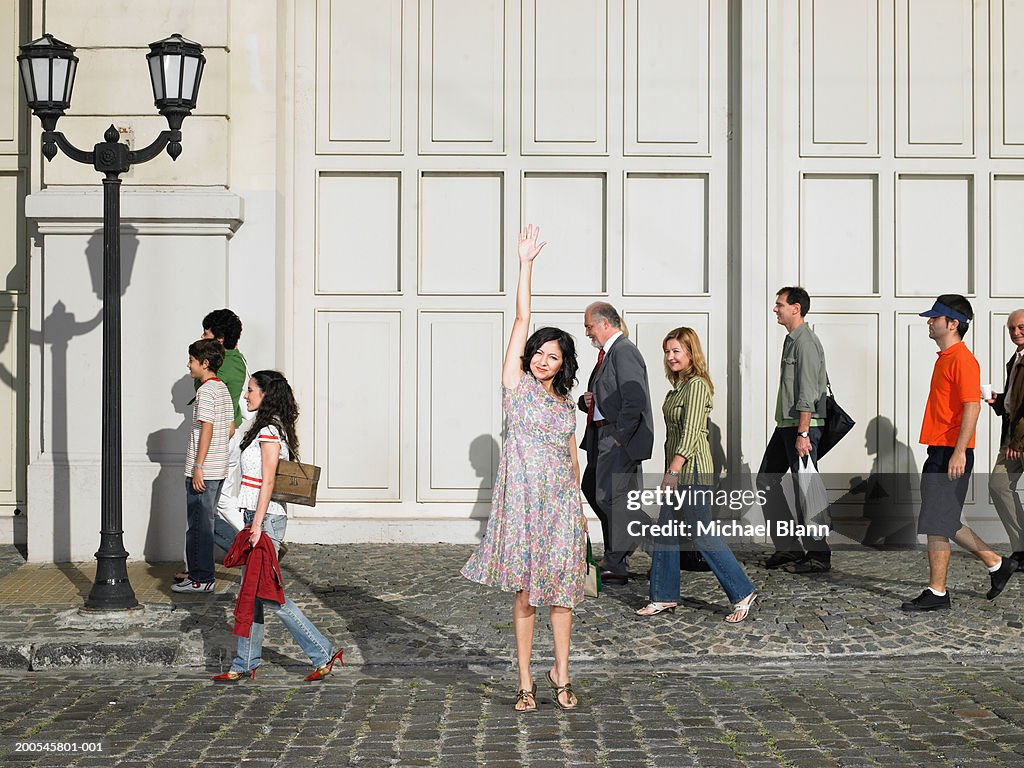 Woman standing in street with hand raised, portrait