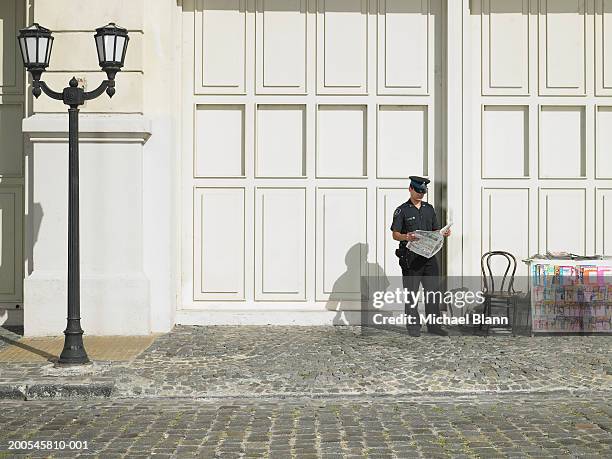policeman standing by stall in street reading newspaper - le cap - fotografias e filmes do acervo