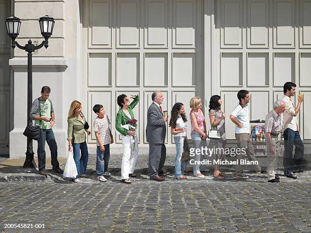 long queue of people in street, side view - waiting foto e immagini stock