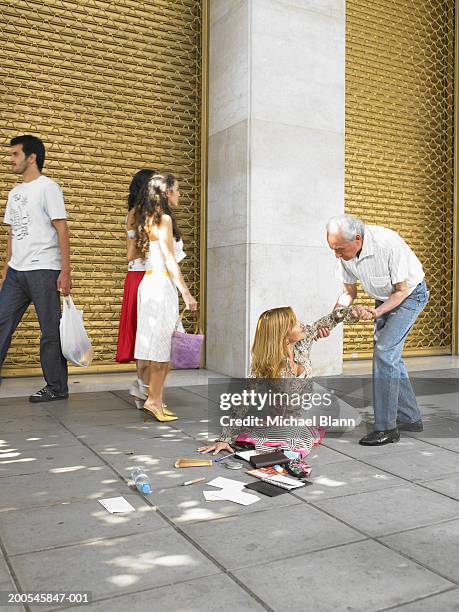 senior man helping woman fallen on street - caballerosidad fotografías e imágenes de stock