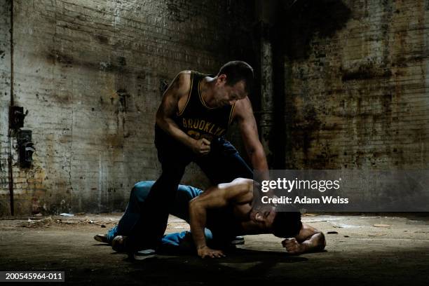 two men fighting in empty industrial space - ruzie stockfoto's en -beelden