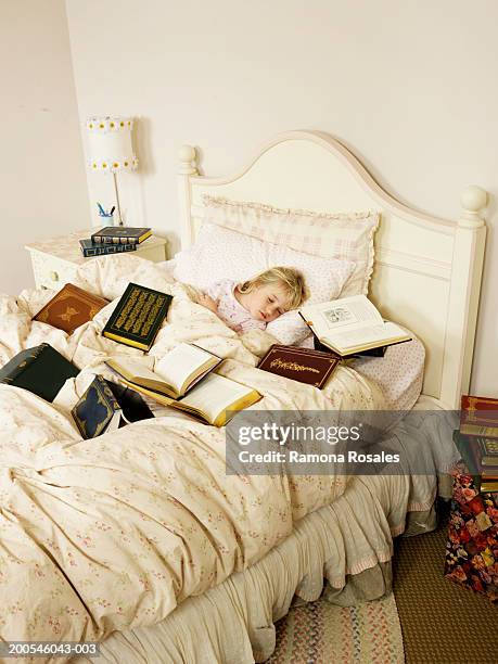 girl (4-6) sleeping in bed surrounded with books - surrounding ストックフォトと画像