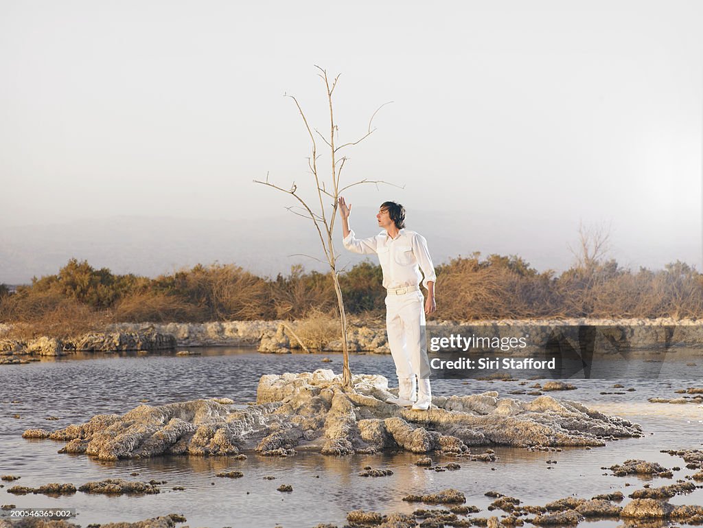 Young man standing on island with tree in marshland