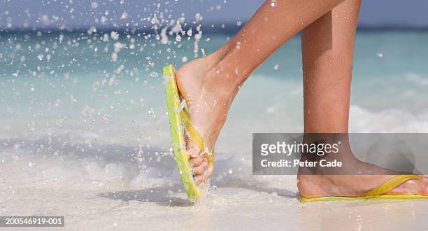 young woman wearing flip-flops walking on beach, low section - thong stock pictures, royalty-free photos & images
