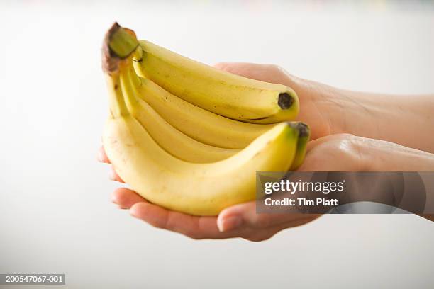 female hand holding bunch of bananas, close-up - ripe stock pictures, royalty-free photos & images