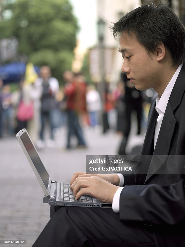 Chinese businessman using laptop in street
