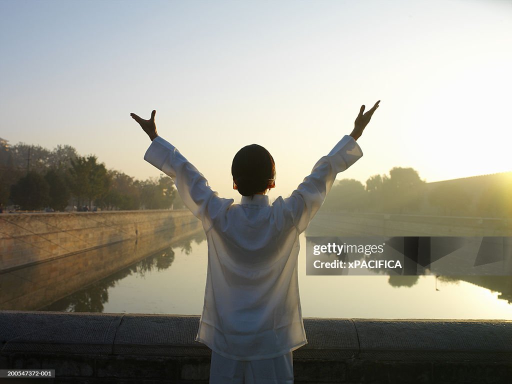 Chinese woman performing tai chi exercises by lake at Forbidden City