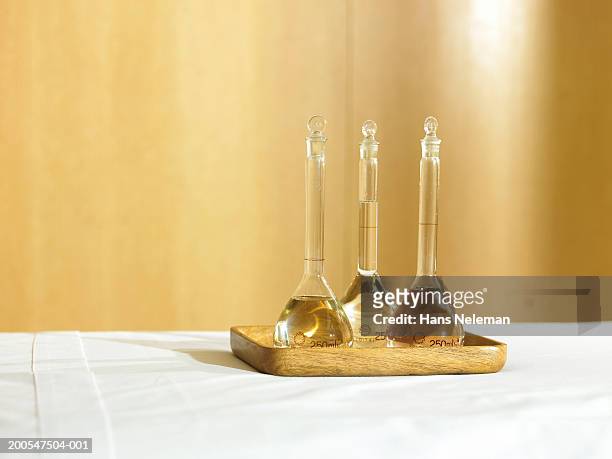 three glass bottles full of oils on a tray on massage bed - aromatherapy oil stock pictures, royalty-free photos & images