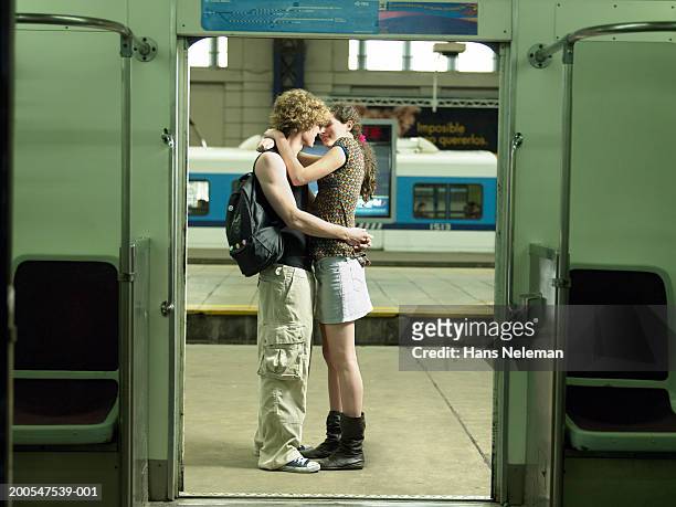 young couple embracing on train station platform, side view - young teen couple stock-fotos und bilder