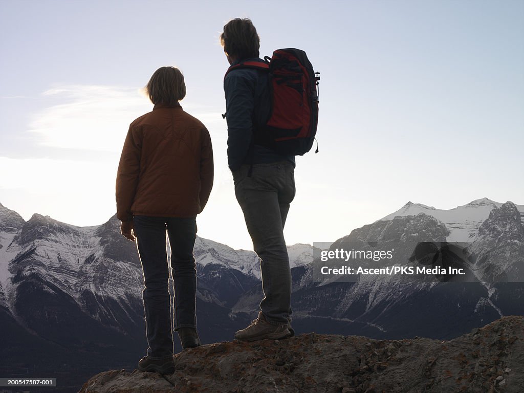 Father and son (14-15) on high mountain ridge, looking at view