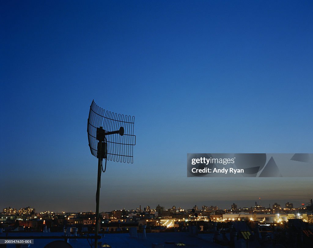 Silhouette of radar antenna, cityscape in background