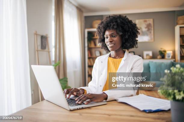 black female doctor using laptop in video call of telemedicine - online therapy stock pictures, royalty-free photos & images
