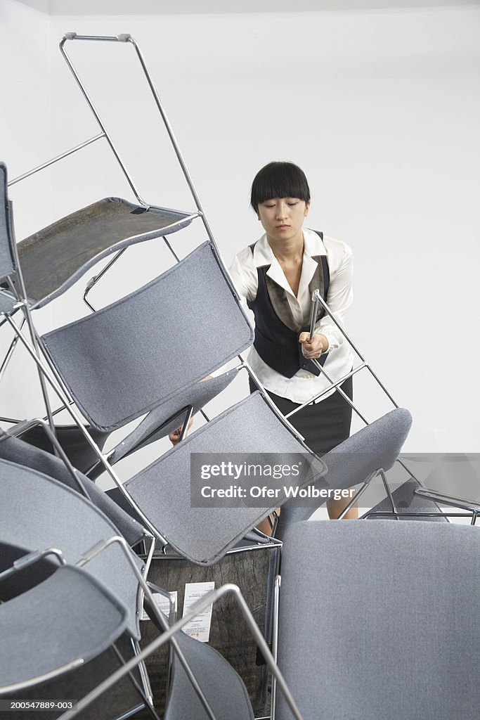 Young woman leaning towards upturned chairs