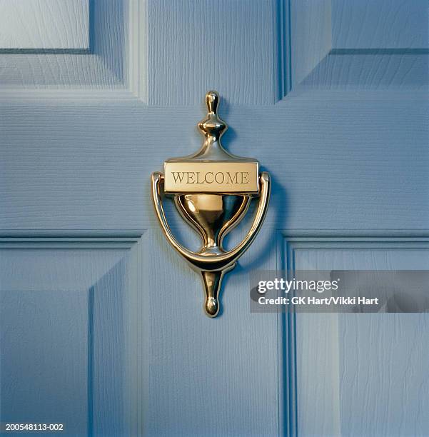 brass door knocker on front door engraved with word 'welcome', close-up - door knocker stock-fotos und bilder