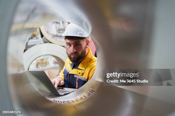 technical engineer is inspecting equipment in a metal steel row - rohstoffverarbeitende fabrik stock-fotos und bilder