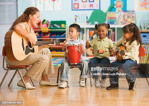 schoolchildren (4-5) playing musical instruments with teacher in classroom - percussion instrument stock pictures, royalty-free photos & images