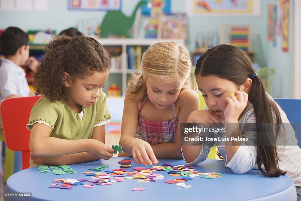 Girls (4-7) playing jigsaw puzzle in classroom