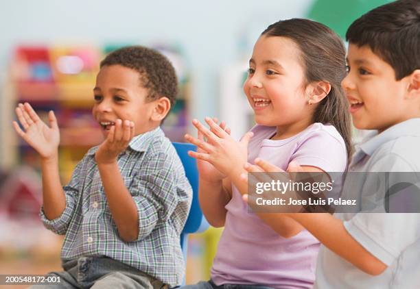 schoolchildren (2-5) sitting in the classroom, clapping, smiling - kids clapping class stock pictures, royalty-free photos & images