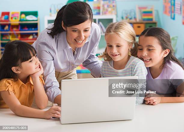 teacher standing by students (4-7) using laptop, smiling - 5 years stock pictures, royalty-free photos & images