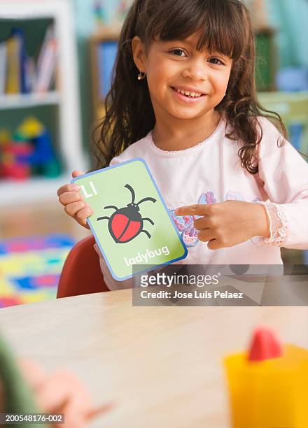 schoolgirl l(4-5) holding ladybug card, smiling, portrait - flash card stock pictures, royalty-free photos & images