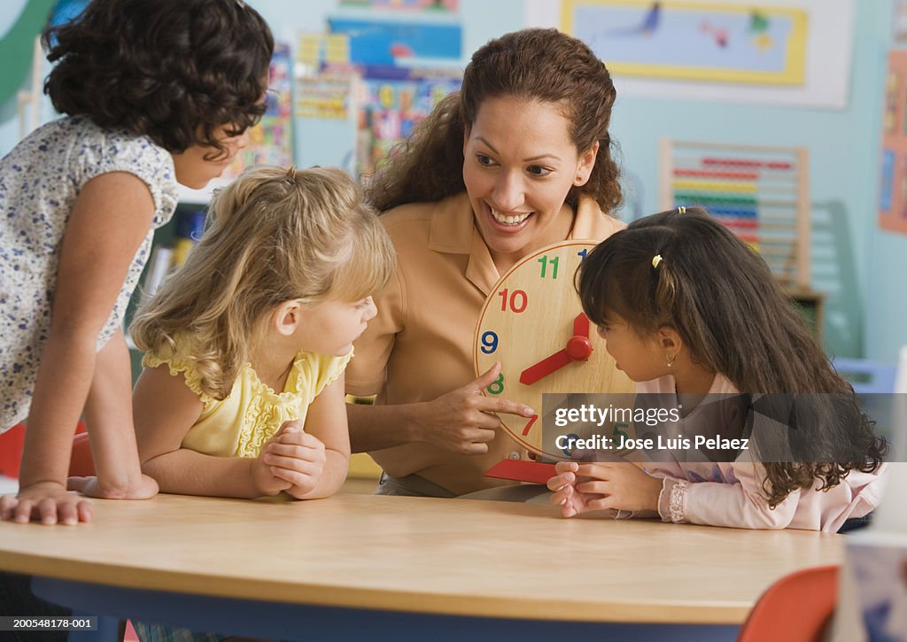 Teacher showing students (4-7) clock in classroom