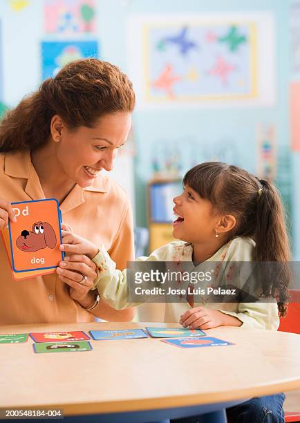 teacher with girl (4-5) holding up flash card of a cat in classroom - flash card stock pictures, royalty-free photos & images
