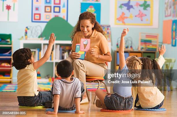 teacher holding up different flash card in classroom, children (4-7) raising hands - leselernkarte stock-fotos und bilder