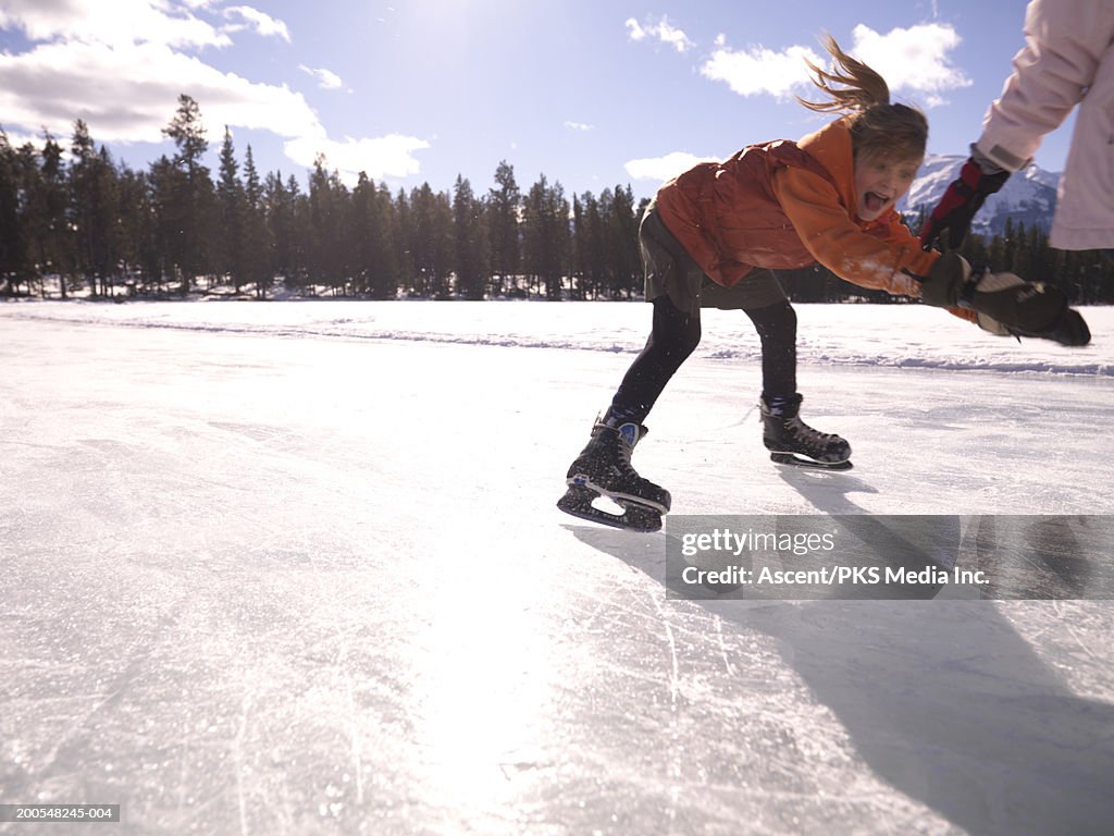 Girl (10-11) ice skating on frozen pond, screaming