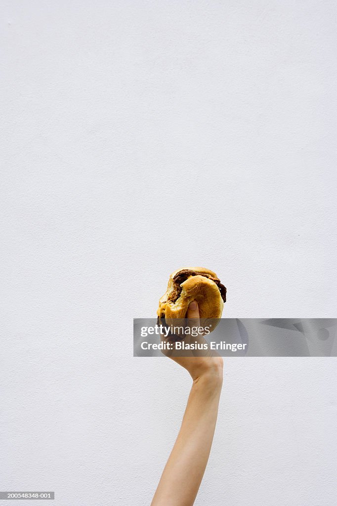 Teenage boy (13-14) holding a bitten hamburger