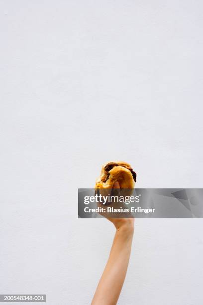teenage boy (13-14) holding a bitten hamburger - burger stock-fotos und bilder