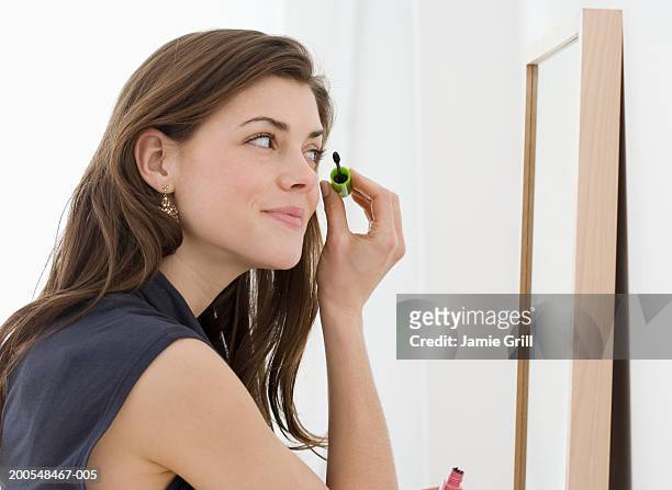 young woman applying mascara in mirror, smiling - mascaras 個照片及圖片檔