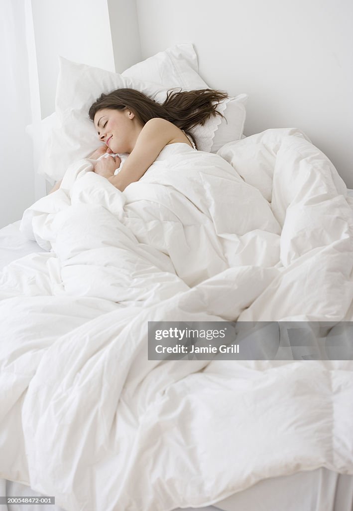 Young woman sleeping in bed, elevated view