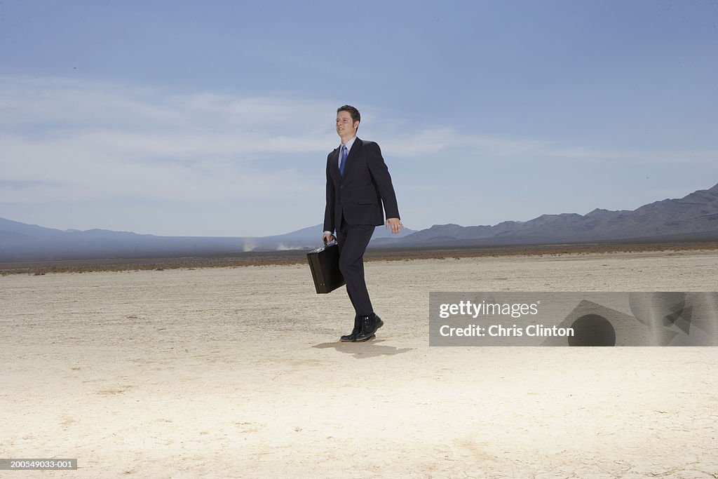 Businessman walking in dry lake bed