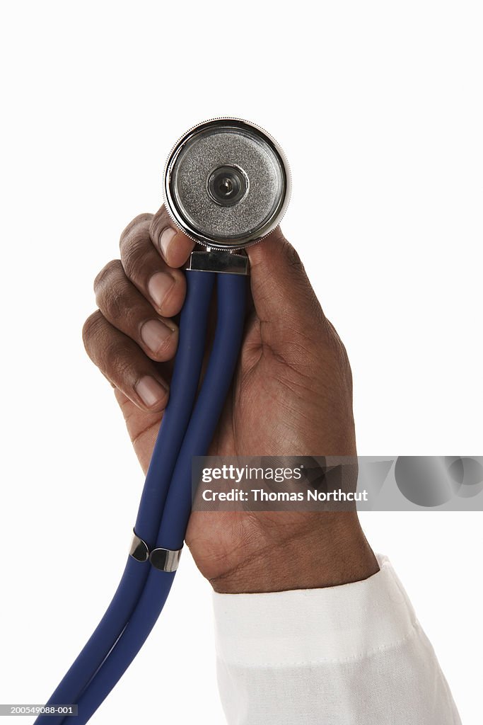 Young male doctor holding stethoscope, close-up of hand