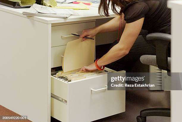 businesswoman filing papers in desk cabinet - filing cabinet stock pictures, royalty-free photos & images