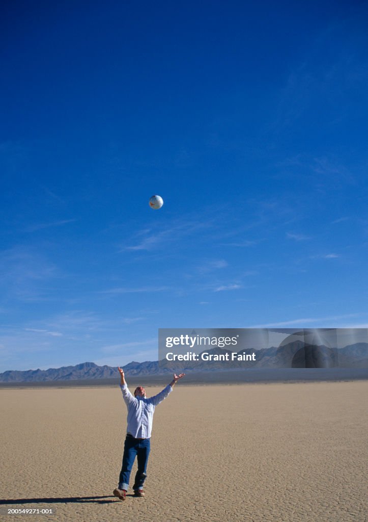 USA, Nevada, man throwing globe into the air in desert